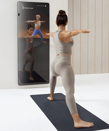 a woman standing in front of a mirror doing a yoga pose with her arms out